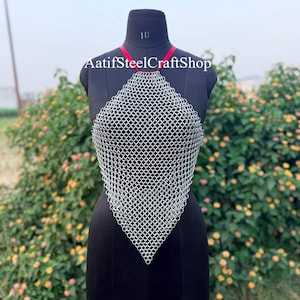 Könnte beinhalten: Ein silberfarbenes Kettenhemd-Halter-Top aus ineinandergreifenden Metallringen in Rautenform. Das Kleidungsstück verfügt über einen roten Riemen um den Hals und zeigt den Text AatifSteelCraftShop im oberen Bereich des Kleidungsstücks.