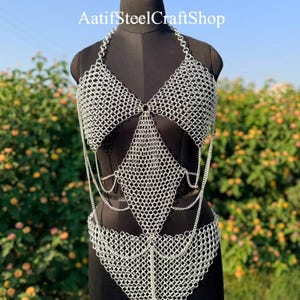Könnte beinhalten: Ein silberfarbener Kettenhemd-Körpergurt mit einem Neckholder-Oberteil mit dreieckigen Körbchen, einem rautenförmigen Mittelteil und einem unteren Taillenstück, die alle durch feine Metallglieder verbunden sind. Der Text AatifSteelCraftShop ist sichtbar.