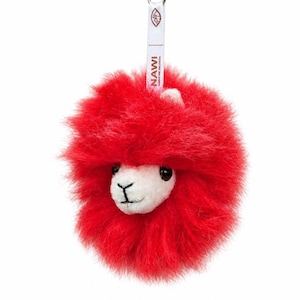 Op de afbeelding: Een rode pluche lama sleutelhanger met een witte gezicht, zwarte ogen en een zwart gestikte mond. De sleutelhanger heeft een zilveren sluiting en een witte band met de tekst "NAWI" en een logo.