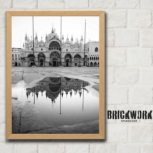 Peut inclure: Impression en noir et blanc encadrée de la basilique Saint-Marc à Venise, en Italie, reflétée dans une flaque d'eau. L'image est dans un cadre en bois et est affichée contre un mur de briques blanches. Le texte "BRICKWORK STUDIO ART" est visible.