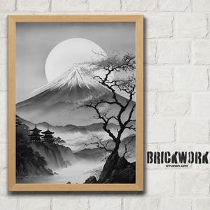 May include: Black and white framed print of a Japanese landscape featuring Mount Fuji, a large sun, and a tree. Two pagodas sit on a cliff overlooking a misty valley. The artwork is framed in a light brown wooden frame.