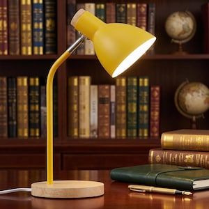 May include: A yellow desk lamp with a wooden base and a flexible neck. The lamp has a bright light and is positioned on a wooden desk. The background features a bookshelf filled with books and a globe.