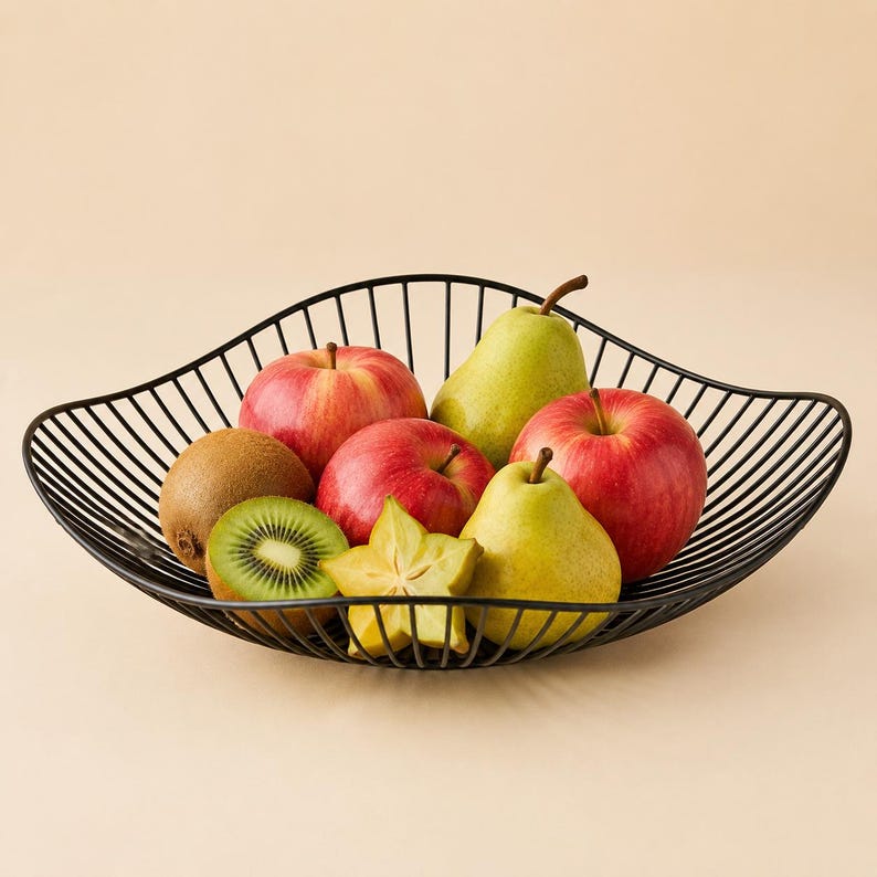 May include: A black wire fruit bowl with a wavy rim containing a variety of fresh produce including two red apples, two green pears, a whole brown kiwi, a sliced green kiwi, and a yellow starfruit arranged inside the metal structure.