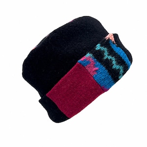 May include: A black knit beanie featuring a wide, solid maroon cuff and a decorative band above it. The band displays a repeating zigzag pattern in vibrant shades of blue, pink, and teal, adding a colorful contrast to the dark, textured fabric.