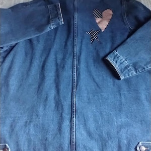 May include: A blue denim jacket with a brown corduroy collar. The jacket has a heart-shaped patch with an American flag design and a star patch on the back.