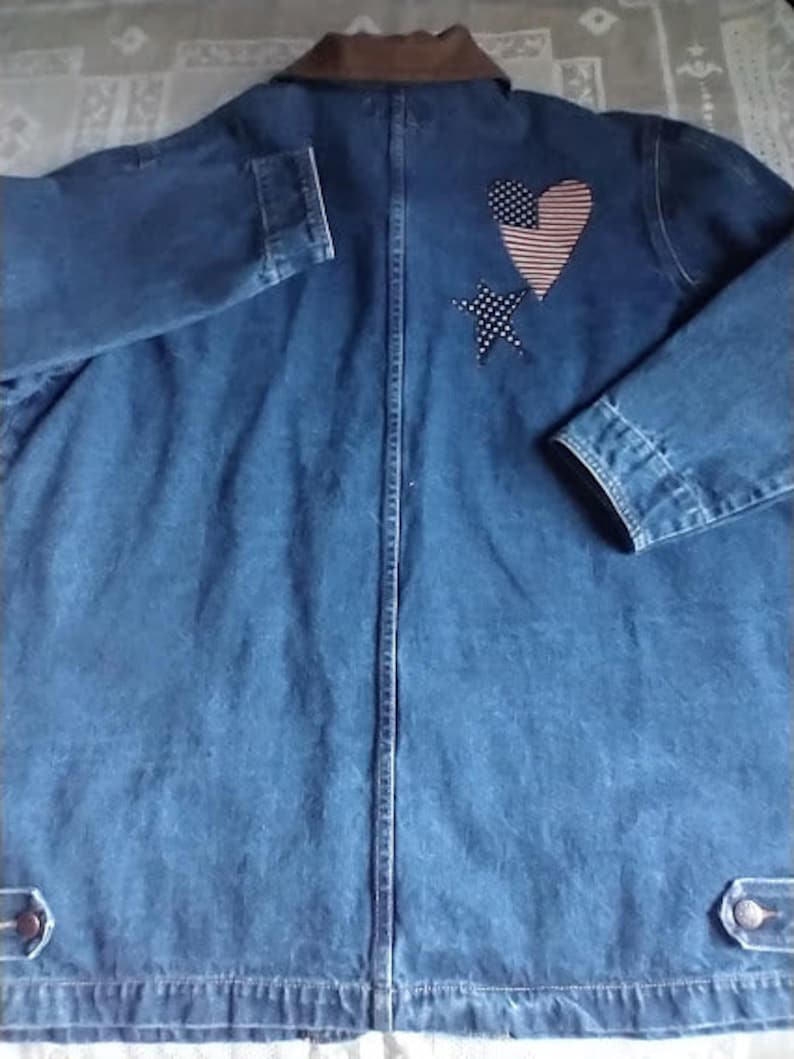May include: A blue denim jacket with a brown corduroy collar. The jacket has a heart-shaped patch with an American flag design and a star patch on the back.