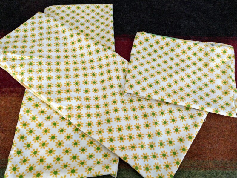 May include: A set of three white fabric pillowcases with a yellow and green daisy print.