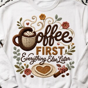 May include: A white sweatshirt featuring a graphic design with the text Coffee FIRST Everything Else Later. The design includes a crocheted coffee mug, a heart-shaped cookie on a plate, cinnamon sticks, and floral accents in brown, pink, and green.
