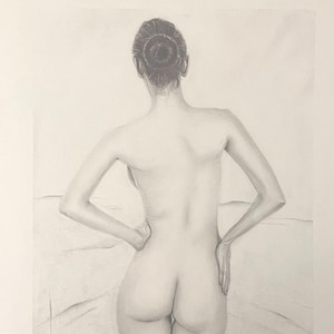 May include: A pencil drawing depicting a person from behind, hands on hips, hair styled in a bun. The artwork uses shades of grey and white, with subtle shading to create a sense of depth and form.