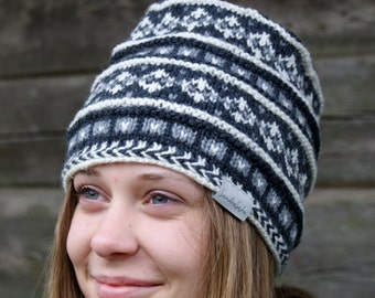 May include: A woman wearing a black and white knitted hat with a white label that says "Sandra Soto".