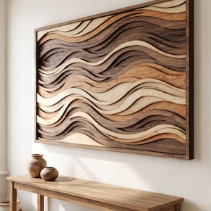 May include: A rectangular wall art piece featuring layered, undulating wooden waves in varying shades of brown, tan, and cream. The artwork is enclosed in a dark wood frame and includes the signature M. Tanaka Designs in the bottom right corner.