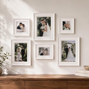 Peut inclure: Un ensemble de six cadres photo blancs de tailles variées, disposés en galerie murale. Chaque cadre contient une photographie de mariage montrant un couple en tenue formelle dans des décors extérieurs, organisés selon une disposition structurée.