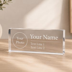 Peut inclure: Un bloc de bureau rectangulaire en acrylique transparent avec un motif gravé en blanc. Le côté gauche présente un cadre circulaire avec le texte Your Photo. Le côté droit inclut le texte Your Name au-dessus de Text Line 1 et Text Line 2.
