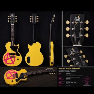 Peut inclure: Une guitare électrique jaune avec un manche et une tête noirs, ornée d'un symbole d'anarchie rose sur le corps. La guitare est présentée sous plusieurs angles, mettant en valeur son design et ses détails. La tête porte les logos "RnR" et "Relic Retro".