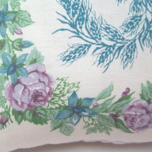 Puede incluir: Una tela blanca con un patr&oacute;n floral que presenta flores azules y moradas, hojas verdes y espigas de trigo. La tela tiene una est&eacute;tica vintage.