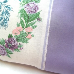 Puede incluir: Una almohada blanca con un patr&oacute;n floral con flores rosas, moradas y verdes. La almohada tiene un respaldo de color lavanda.