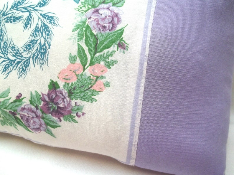 Puede incluir: Una almohada blanca con un patr&oacute;n floral con flores rosas, moradas y verdes. La almohada tiene un respaldo de color lavanda.