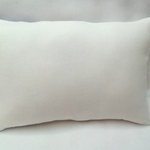 Puede incluir: Una almohada rectangular blanca lisa con una superficie de tela suave y lisa.