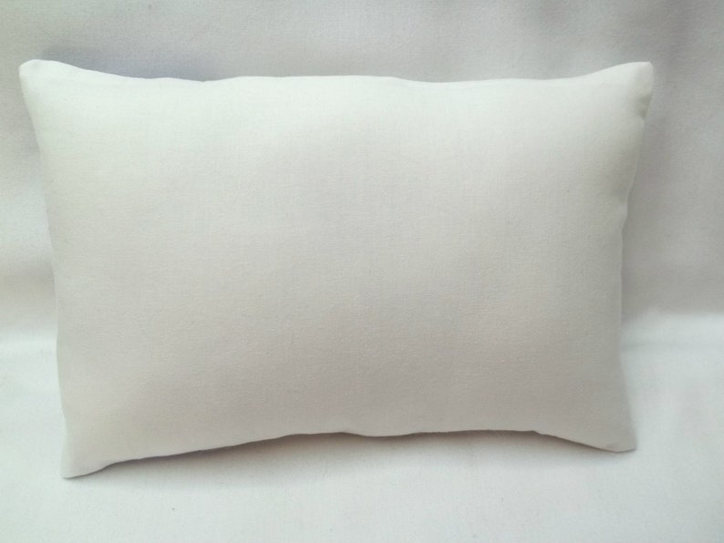 Puede incluir: Una almohada rectangular blanca lisa con una superficie de tela suave y lisa.