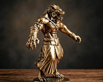 May include: A bronze-colored figurine of a lion-headed humanoid creature. The figure is posed with arms outstretched, wearing a loincloth and armbands. The statue is on a round base, set against a dark background.