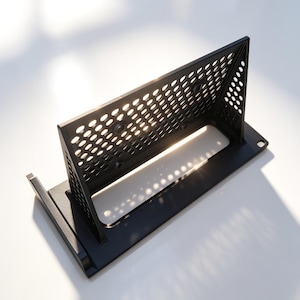Puede incluir: Un soporte de montaje en rack de plástico negro para receptor Shure PGX4, con una base rectangular y un panel trasero inclinado y perforado con recortes circulares. El texto "Supporto ricevitore Shure PGX4" aparece en la parte inferior.