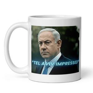 Peut inclure: Mug en céramique blanche avec un portrait d'homme en costume et cravate bleue. Le texte "*TEL AVIV IMPRESSED*" est en bleu. La tasse a une anse incurvée.