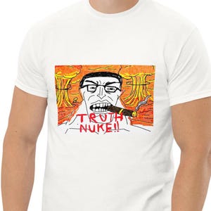 Puede incluir: Una camiseta blanca con una ilustración gráfica de una persona con gafas fumando un puro. El fondo muestra nubes de hongo naranjas y amarillas. El texto TRUTH NUKE!! está impreso en letras rojas debajo de la barbilla de la persona.