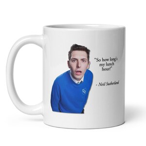 May include: White ceramic mug featuring a person in a blue sweater with the quote "So how long's my lunch hour?" by Neil Sutherland. The mug has a large handle and a glossy finish.