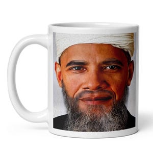Puede incluir: Una taza de cerámica blanca con un retrato detallado y realista de una persona de tez bronceada, ojos oscuros y una barba larga y canosa. El individuo lleva un tocado de color claro y textura que se envuelve alrededor de la frente.