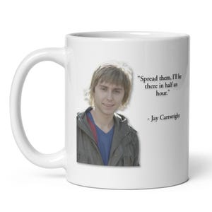 May include: White ceramic mug featuring a photo of a man and a quote: "Spread them, I'll be there in half an hour." The quote is attributed to Jay Cartwright. The mug has a white handle.