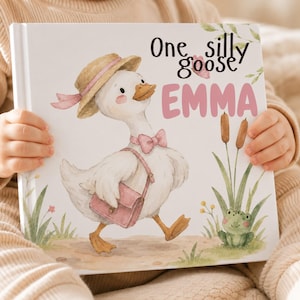 May include: A hardcover children's book with a white cover featuring a watercolor illustration of a white goose wearing a straw hat, a pink bow tie, and a pink satchel. The text reads One silly goose EMMA in black and pink lettering.