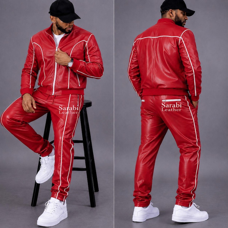 May include: A red leather tracksuit featuring a zip-up jacket and matching pants with white piping accents. The jacket has a stand-up collar and long sleeves. The pants have a straight-leg fit. The text Sarabi Leather is printed on the pants.