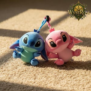 Puede incluir: Dos figuras de peluche, una azul y otra rosa, est&aacute;n conectadas por una cuerda azul y rosa. La figura azul tiene ojos negros grandes y orejas grandes. La figura rosa tiene una corona y ojos negros grandes. Los juguetes est&aacute;n sobre una alfombra beige.