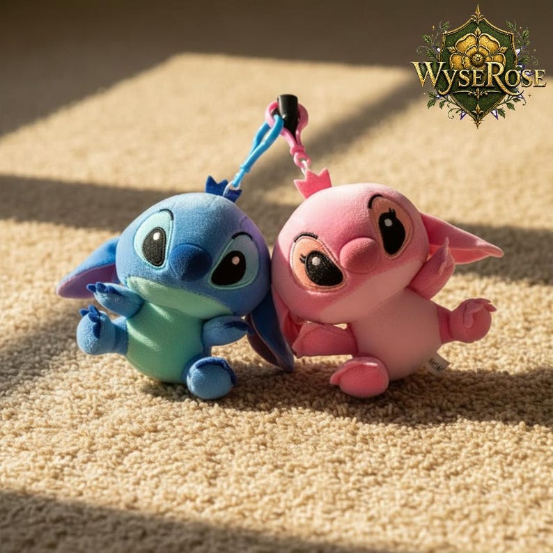 Puede incluir: Dos figuras de peluche, una azul y otra rosa, est&aacute;n conectadas por una cuerda azul y rosa. La figura azul tiene ojos negros grandes y orejas grandes. La figura rosa tiene una corona y ojos negros grandes. Los juguetes est&aacute;n sobre una alfombra beige.