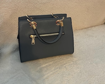 Bolso de mano tipo satchel estructurado de piel sintética Saffiano: Elegancia en piel sintética de grano cruzado resistente a los arañazos.