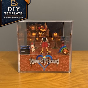 May include: A clear acrylic cube display featuring a Kingdom Hearts diorama. Inside, a character stands before a building with an Items sign, accompanied by a small white creature. The base displays the Kingdom Hearts logo and game menu elements.