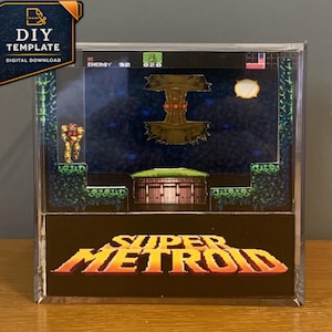 Könnte beinhalten: Eine quadratische, durchsichtige Acryl-Displaybox mit einem geschichteten 3D-Diorama einer Super Metroid-Videospielszene. Die Szene zeigt eine Figur in einem gelben Anzug auf einer grünen Plattform, einen dunklen Hintergrund und das Super Metroid-Logo.