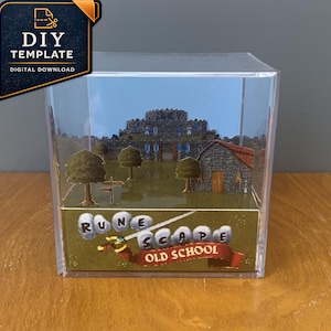 May include: A clear acrylic cube display case containing a multi-layered paper diorama of a castle scene. The front panel features the text RuneScape Old School with a sword graphic. The interior depicts a stone castle, trees, and a building.