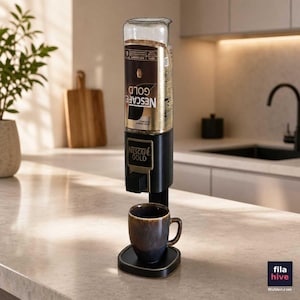 May include: A black coffee dispenser stand holding an inverted Nescafé Gold glass jar with a black and gold label. The dispenser features a black dispensing mechanism positioned directly above a dark brown ceramic mug resting on a black base.