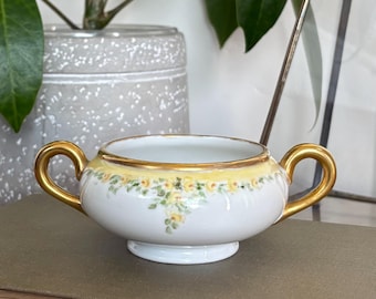 Bol antiguo de porcelana con dos asas, decorado con rosas amarillas pintadas a mano y ribete dorado.
