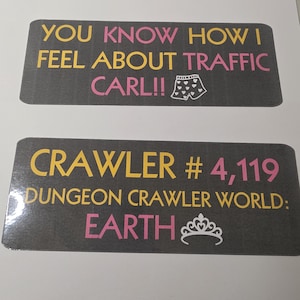 Könnte beinhalten: Zwei rechteckige Aufkleber mit Text. Der obere Aufkleber lautet "YOU KNOW HOW I FEEL ABOUT TRAFFIC CARL!!" in Gelb und Pink. Der untere Aufkleber lautet "CRAWLER # 4,119 DUNGEON CRAWLER WORLD: EARTH" in Gelb und Pink.