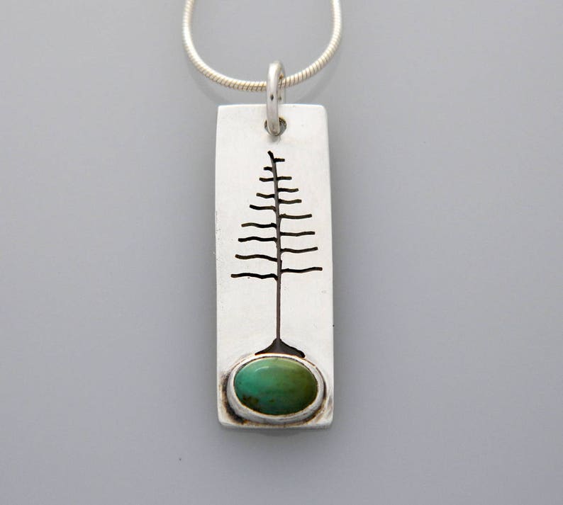 May include: A silver pendant necklace with a turquoise stone and a tree design. The pendant is rectangular and has a silver chain.