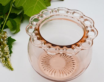 May include: A vintage pink glass bowl with a scalloped edge. The bowl has a textured, sunburst pattern on the bottom.