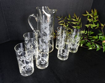 May include: A set of clear glass etched with a floral design. The set includes a pitcher and six glasses.