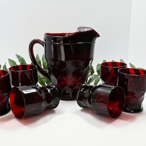 May include: A set of six ruby red glass tumblers and a matching pitcher. The glasses and pitcher have a textured, diamond-shaped pattern.