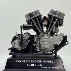 May include: A detailed scale model of a V-twin Panhead engine featuring metallic silver and black components. The engine is mounted on a black rectangular base with the text "PANHEAD ENGINE MODEL 1948-1965 made by Scale Model Choppers" printed in white.