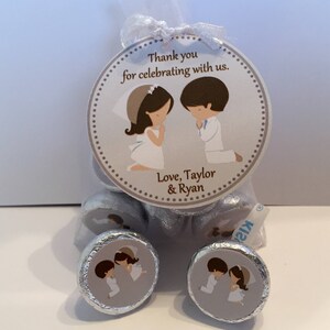 May include: A silver bag filled with chocolate kisses with a personalized tag. The tag features a cartoon illustration of a bride and groom with the text "Thank you for celebrating with us. Love, Taylor & Ryan".