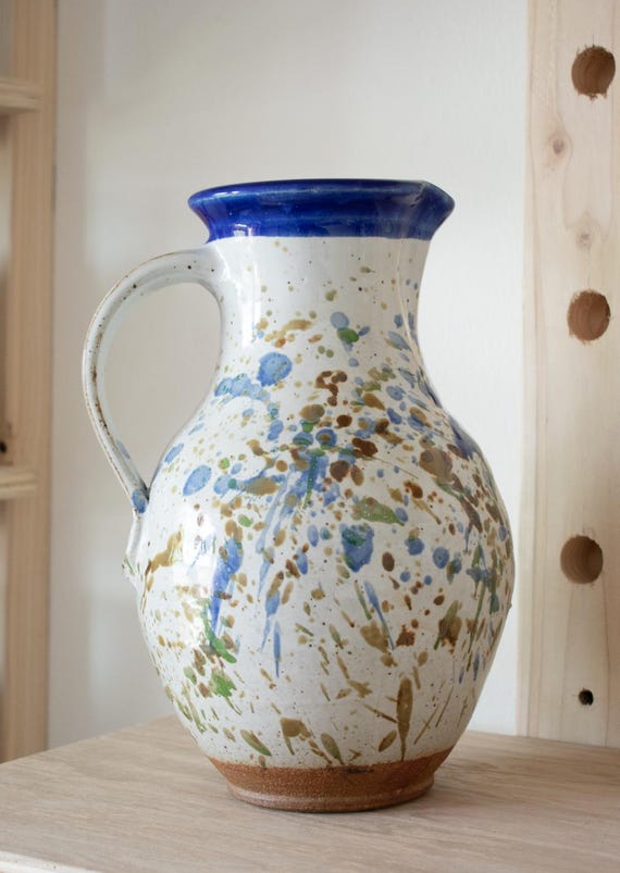 A wheel-thrown stoneware pitcher with a raw canvas-textured glaze that lives on the line between farmhouse functional and gallery-worthy art object.