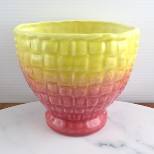 Peut inclure: Un bol en céramique présentant un motif en grille texturé semblable à une gaufre sur l'extérieur. Le bol affiche un dégradé de couleurs, passant d'un jaune vif au bord supérieur à un rose profond à la base, sur un pied piédestal.