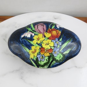 May include: A blue and gold ceramic trinket box with a floral design. The flowers are yellow, red, pink, and blue.